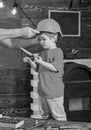 Boy standing behind the table with various tools. Daddy taking care about sons safety. Male hands holding orange Royalty Free Stock Photo