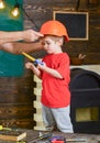 Boy standing behind the table with various tools. Daddy taking care about sons safety. Male hands holding orange Royalty Free Stock Photo