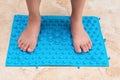 Boy standing on a blue foot massage pad