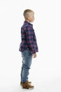 The boy is standing. A cute fat schoolboy in jeans, a shirt and a white T-shirt. Full height. White background. Vertical. Side