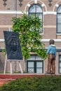 A boy standing in front of a bronze portrait of Rembrandt