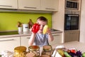 Boy standing in the kitchen and sorting out groceries from the store. Sweet pepper in the hands of a child