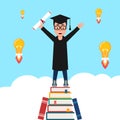 Boy standing on a mountain of books getting ideas. Cheerful student in graduation gown and cap celebrates graduation with a diplom Royalty Free Stock Photo