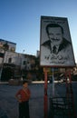 A boy standing next to a picture of Hafez Al'Assad, Syria