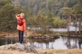 A boy standing on a rock holding a stick, admiring a view of lake, back view, Lake District, UK Royalty Free Stock Photo