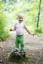 Boy standing on a stump, proud of his achievement of learning to walk the woods Royalty Free Stock Photo