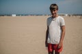 Boy holding mobile phone on the sunny beach and smiling Royalty Free Stock Photo