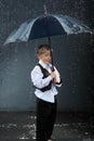 Boy standing under umbrella in rain