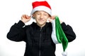 A boy standing on a white background puts a red Santa hat on his head Royalty Free Stock Photo