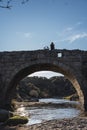 A boy stands on the arch of a Roman bridge with his toy pirate ship looking to the right Royalty Free Stock Photo