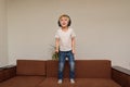 Boy stands on couch in headphones. Child listens to music and dances