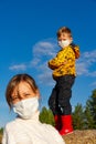 Boy stands on a haystack against a blue sky, his mother stands in front of him