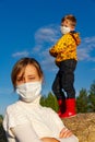 Boy stands on a haystack against a blue sky, his mother stands in front of him