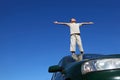 Boy stands on head of car widely placing hands