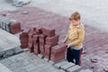 The boy stands near the building bricks. gray and red bricks . Children and professions. Children and construction Royalty Free Stock Photo
