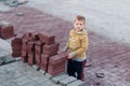 The boy stands near the building bricks. laying paving slabs . Children and the profession Royalty Free Stock Photo