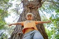 A boy stands near a large tree, wide-angle photo, view from below