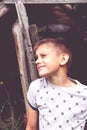 a boy stands near an old wooden booth and looks up squinting