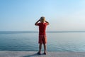 Boy stands on the seafront and looks out to sea. Back view, child on sky and sea background Royalty Free Stock Photo