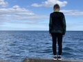 The boy stands on the shore facing the sea. A child on the pier looks at the sea. A teenager by the ocean Royalty Free Stock Photo