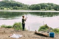 A boy stands on the shore of a lake or river with a fishing rod during a family vacation, a child is waiting for his Royalty Free Stock Photo