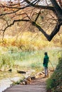 Boy stay near pond in autumn park, last sunny autumn days Royalty Free Stock Photo