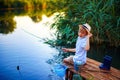 Boy in straw hat with a fishing rod catches fish on riverbank at golden hour of sunset, river Royalty Free Stock Photo