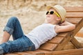 The boy in the straw hat lying on the wooden sun loungers on the beach.Summer vacation. Royalty Free Stock Photo