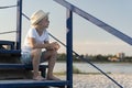 Boy in straw hat sitting on stairs in beach background. Summer vacation