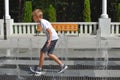 Boy is having fun in the street fountain. Summer children`s games in the park. Royalty Free Stock Photo