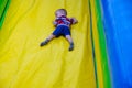 A boy in a striped T-shirt, blue shorts rolls off an inflatable slide. Happy childhood. Outdoor games Royalty Free Stock Photo