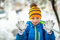 Boy student in blue jacket showing palms in gloves covered with snow during snowfall in city Royalty Free Stock Photo