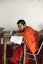 Boy student Buddhist monk studying at a Buddhist school. Boy student Buddhist monk in an orange robe writing pen.