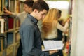 Boy student in library want to find some book. Student getting ready to exam