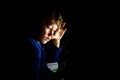 Boy studying mathematics at night alone in his dark room with Montessori material