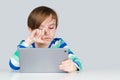 Boy studying online on laptop at home. Tired little student feeling eyestrain during online lesson Royalty Free Stock Photo