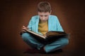 A boy in a suit sits with a book