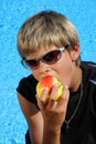 Boy with sun glasses and t-shirt eating an apple Royalty Free Stock Photo