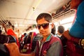 Boy in sunglasses standing inside crowded bus