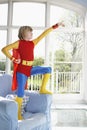 Boy In Superman Costume On Armchair Pointing Up