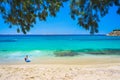 Boy with surf board at the tropical beach of Agios Stefanos with tamarisk and turquoise water, Mykonos island, Greece Royalty Free Stock Photo