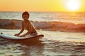 Boy surfer getting ready for ride on the ocean wave against beautifull sinset light Royalty Free Stock Photo