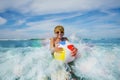 Boy swim at ocean waves in sunglasses with color inflatable ball Royalty Free Stock Photo