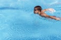 Boy swimmer swimming butterfly stroke in pool. Young athlete swim in swimming pool. Training, competition, water sports Royalty Free Stock Photo