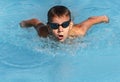 Boy swimmer swimming butterfly stroke in pool. Young athlete swim in swimming pool, training, competition, water sports Royalty Free Stock Photo