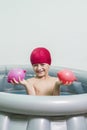 Boy with a swimming cap showing two water balloons