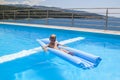 a boy is swimming on a mattress in the pool in the Villa Royalty Free Stock Photo