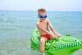 BOY SWIMS IN THE SEA ON THE INFLATABLE CROCODYLE TOY Royalty Free Stock Photo
