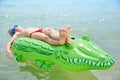 BOY SWIMS IN THE SEA ON THE INFLATABLE CROCODYLE TOY