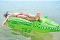 BOY SWIMS IN THE SEA ON THE CROCODYLE TOY